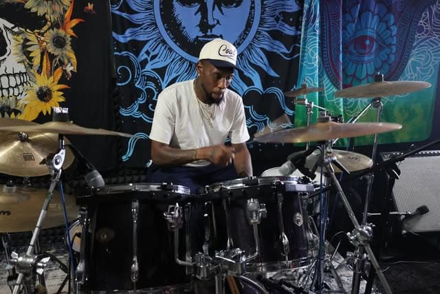 Gumbo's drummer behind the kit, blue sun tapestry behind him